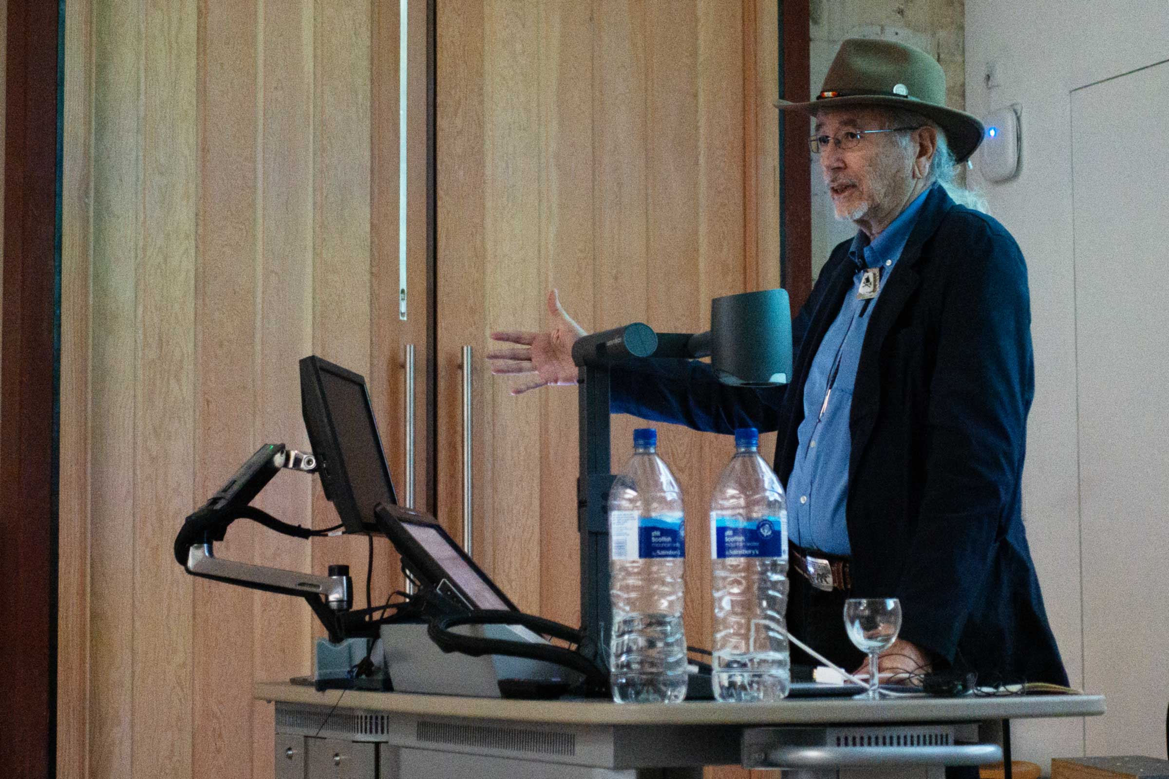 Man standing and talking next to a podium in an event hall.