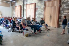 June Jones speaking at the Dead Images Conference, Edinburgh College of Art, July 2018. Woman standing and talking to an audience in an event hall.