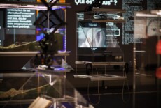 Display case with a video screen in it in a dark exhibition space.