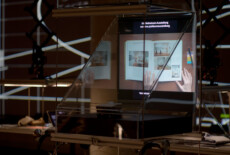 Display case with a video screen in it in a dark exhibition space.