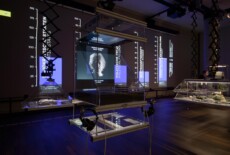 Display case with a video screen in it in a dark exhibition space.