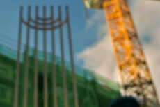 Eduard-Wallnoefer-Platz, Innsbruck, Tyrol, 2012 Out of focus building under construction, a large crane, and a tall seven-branch menorah. In the foreground and in focus is a long bubble level.