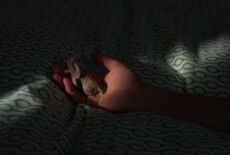 Hand holding a small grey piece of yarn or textile