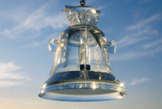 Crystal glass bell created for the reconstructed former House of the Fascist Party in Predappio, Italy. Still from an AI-generated sequence in Fragile Power, 2026. Glass bell with Fascist decorations against blue sky.